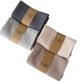 Two light grey cotton waffle kitchen towels with honeycomb texture folded neatly on a wooden counter